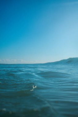 Kırılan dalgalar ve sprey, hareket eden suyun yüzeyine yansıyan beyaz su ve ışık.