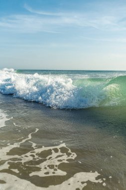 Kırılan dalgalar ve sprey, hareket eden suyun yüzeyine yansıyan beyaz su ve ışık.