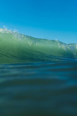 Kırılan dalgalar ve sprey, hareket eden suyun yüzeyine yansıyan beyaz su ve ışık.