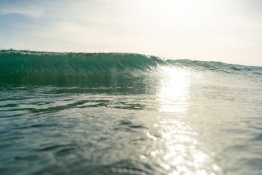 Kırılan dalgalar ve sprey, hareket eden suyun yüzeyine yansıyan beyaz su ve ışık.