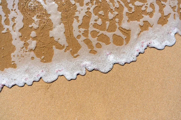 Top view of a wave breaking on the sand at the beach