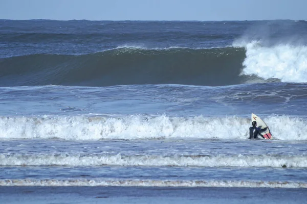 대서양 포르투갈의 해변에서 파도가 부서지고 가운데 파도타기하는 사람이 파도타기를 — 스톡 사진