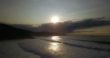 Kuzey İspanya 'nın kayalık kıyı şeridine ait İHA görüntüleri. Gün batımında gelen dalgalar, bulutlar ve güneş ışığıyla dolu bir sahil.