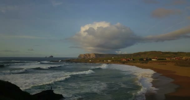 スペイン北部の岩場の海岸線のドローン映像日没時に波 太陽の光が入るビーチ — ストック動画