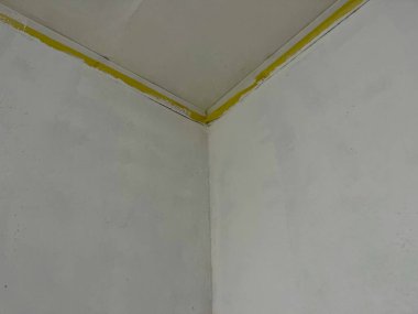 Boya silindiri, koruma altındaki ahşap zemindeki beyaz boyayla dolu tepside dinleniyor. İç yenileme süreci, duvar boyama ve ev geliştirme konsepti.