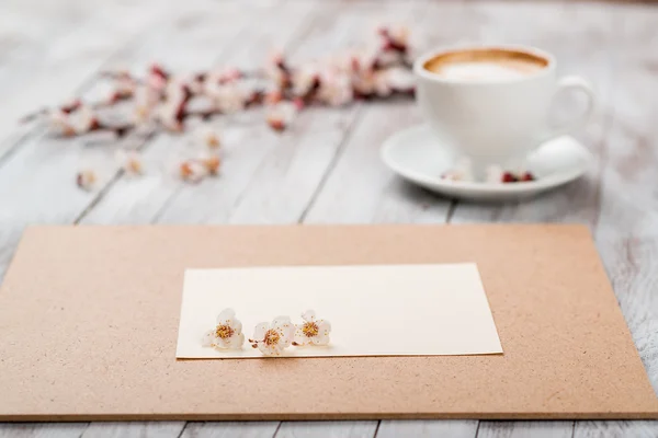 Una taza de café junto a las flores blancas de primavera en textu de madera — Foto de Stock