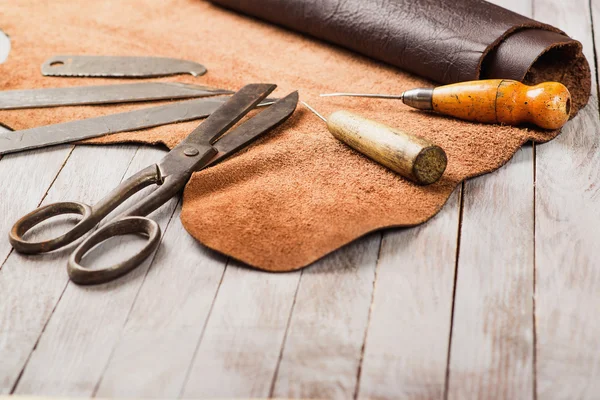 Рабочий стол Кожевника. Кусочки шкуры и кожаные рабочие инструменты на рабочем столе . — стоковое фото
