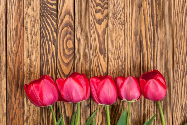 Tulipani rossi su uno sfondo di legno. Spazio per il testo. Vista dall'alto — Foto Stock