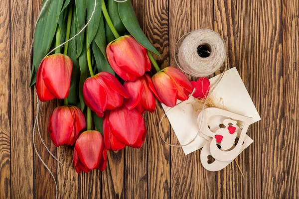 赤いチューリップの花束と木製の背景に粗い糸で装飾。トップ ビュー — ストック写真