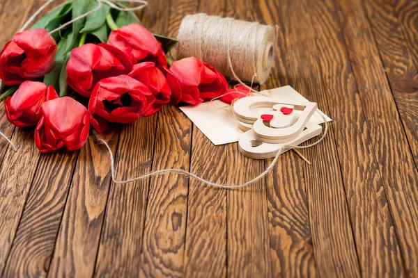 赤いチューリップの花束と木製の背景の並目ねじと装飾. — ストック写真