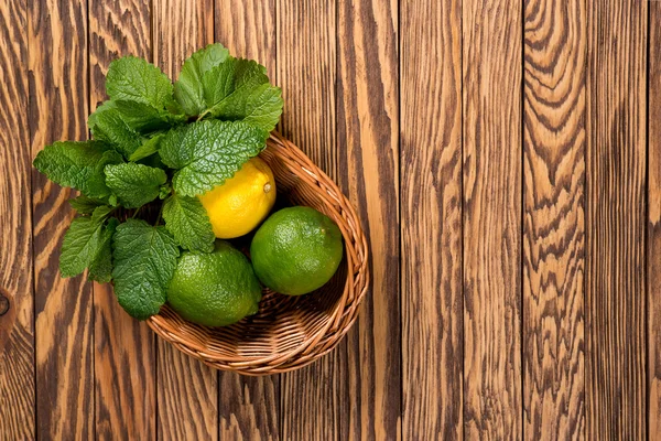 Gul citron, lime och grön mynta blad på en trä bakgrund. Ovanifrån. — Stockfoto