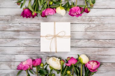 Güzel çiçekler peonies hafif ahşap arka plan üzerinde hediye kutusu ile. Üstten Görünüm.