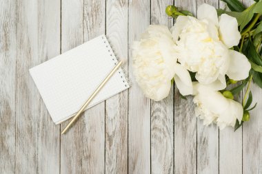 Defter ve kalem beyaz boyalı ahşap plakalar üzerinde Peonies çiçeklerle beyaz. Metin için yer. Üstten Görünüm.