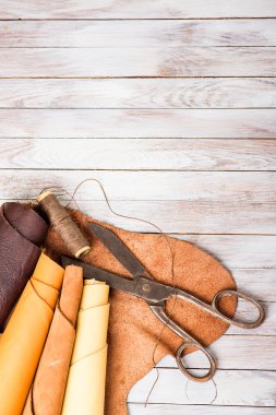 ahşap bir arka plan üzerinde makas ve iplik ile deri rulo