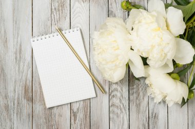 Defter ve kalem beyaz boyalı ahşap plakalar üzerinde Peonies çiçeklerle beyaz. Metin için yer. Üstten Görünüm.