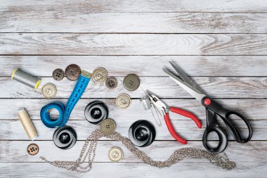 Makas, düğmeler, aksesuar beyaz ahşap zemin üzerinde. El yapımı işyeri. Üstten Görünüm.