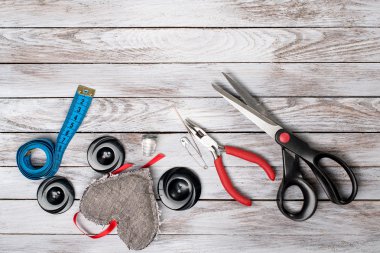 Makas, düğmeler, aksesuar beyaz ahşap zemin üzerinde. El yapımı işyeri. Üstten Görünüm.