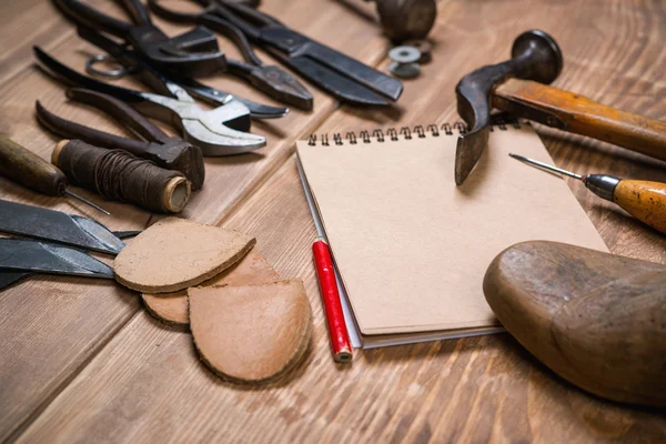 Werkzeugset, Notizbuch, Bleistift für den Schuhmacher auf Holzgrund. — Stockfoto