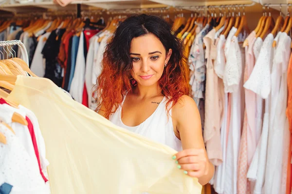 Mladá hezká žena se snaží na nové šaty v obchod s oblečením. Čas na nákupy. Letní výprodej. — Stock fotografie