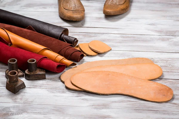 Set of leather in rolls, craft tools on white wooden background. Workplace for shoemaker. Working handmade tools on a work table. — Stock Photo, Image