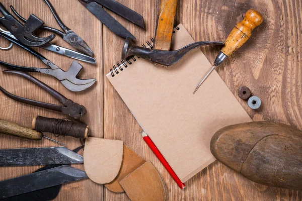 Juego de herramientas, cuaderno, lápiz para zapatero sobre fondo de madera . —  Fotos de Stock