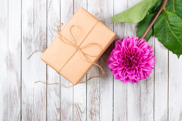 Geschenkbox und rosa blühende Chrysanthemenblume auf Holzgrund. Raum für Text. — Stockfoto