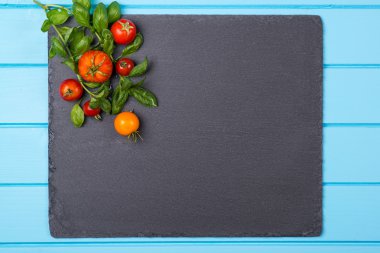 Taze domates ve fesleğen siyah yeni bir sayfa üzerinde. . Metin için yer.