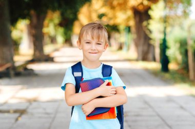 Not defterleri ve sırt çantalı mutlu çocuk çalışmaya hazır. Okul konseptine geri dönelim. Akıllı okul çocuğu dışarıda kitap tutuyor. Eğitim ve ilkokul. Okul çantalı küçük öğrenci..