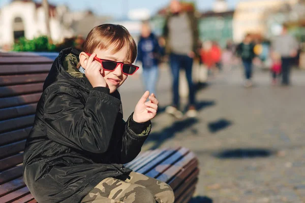 벤치에 귀여운 자켓과 유행하는 선글라스를 소년들의 시절의 — 스톡 사진