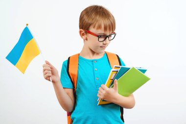 Öğrenci çocuk Ukraynaca öğreniyor. Sırt çantalı sevimli çocuk Ukrayna bayrağı taşıyor. İnsanlar, eğitim, öğrenme ve okul konsepti. Elinde kitaplarla gezen küçük bir öğrenci..