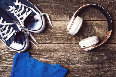 Kırsal alanda kulaklık ve spor ayakkabılar. Moda erkek aksesuarları, üst manzara. Moda ayakkabıları, güneş gözlükleri ve modern kablosuz kulaklıklar. Erkek modası. Uzayı kopyala Hippi kentsel tarzı