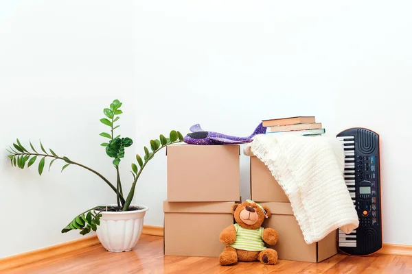新家的概念 玩具和植物在空房间里 一堆堆纸板箱搬家日和房地产的概念 有孩子的年轻家庭的新公寓 — 图库照片
