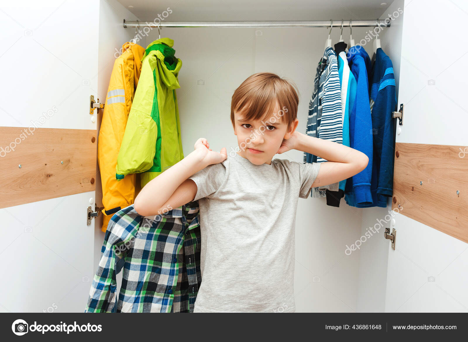 少年は家のワードローブクローゼットで服を選ぶ 可愛い男の子が学校のシャツを着ている ワードローブの服を整理する子供 クローゼットの中で注文 子供服のワードローブ ストック写真 C Volurol