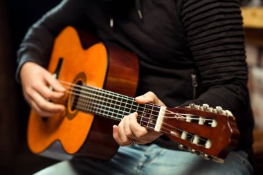 Gitar çalan adamın elleri. Gitarist elinde akustik gitar tutuyor. Barda gitar çalan yakışıklı adam. Gitar çalma pratiği. Müzik konsepti.