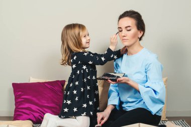 Anne ve kızı makyaj yapıyor. Sevgili anne ve çocuk birlikte eğleniyorlar. Anneler Günün kutlu olsun. Sağlıklı çocuk kozmetik ürünleri. Mutlu sevgi dolu aile.