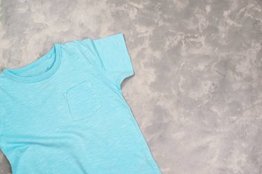 Fotokopi alanı olan mavi renkli tişört. Tişört modeli, düz yatış. Modern beton arkaplan.