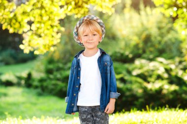 Yaz parkında poz veren şık küçük çocuk. Moda, yaşam tarzı ve yaz konsepti. Güneşli bir günde mutlu çocuk yürüyüşü. Moda kıyafetler ve şapka giyen yakışıklı çocuk..