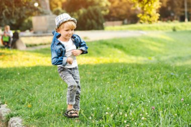 Yaz parkında poz veren şık küçük çocuk. Moda, yaşam tarzı ve yaz konsepti. Güneşli bir günde mutlu çocuk yürüyüşü. Moda kıyafetler ve şapka giyen yakışıklı çocuk..