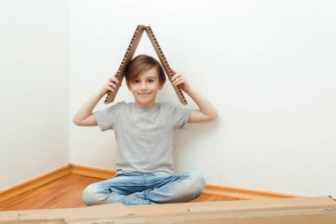 Mutlu çocuk yeni evinde çatının sembolünü yapıyor. Çocuklu genç bir ailenin evi. Tatlı çocuk yeni aile evimizi düşlüyor..