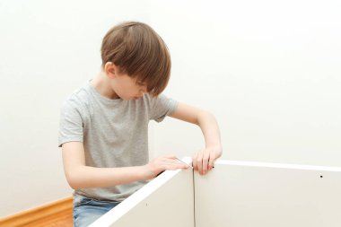 Çocuk kendisi bir kitaplık kuruyor. Oğlu evde yeni mobilya montajı için babasına yardım ediyor. Mobilya montajı..