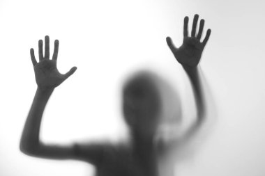 Silüet korkmuş çocuk cam kapının arkasında duruyor. Çocuk iki elini birden gösteriyor. Geçmişi tehlikeli, korku, yardım, musallat olma, korku ve paniği temsil ediyor. Gençlik sorunları, olumsuz duygular kavramı.