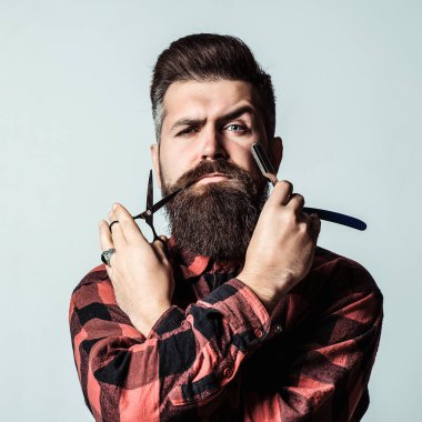 Mavi arka planda jilet ve makaslı berber. Elinde profigüonal aletler tutan zalim bir adam. Berber dükkanı. Erkek tıraşı. Klasik berber dükkanı, tıraş. Berber makası. Klasik düz tıraş bıçağı. Berber dükkanı reklamı..