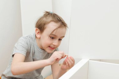 Çocuk kendisi bir kitaplık kuruyor. Oğlu evde yeni mobilya montajı için babasına yardım ediyor. Mobilya montajı..