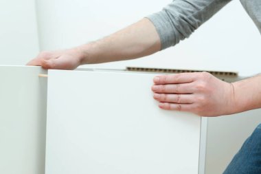 Adam evde yeni mobilya montajı yapıyor. Mobilyaları kendin monte et. Genç işçi bir kitaplık topluyor. Mobilya teması. Müteahhit modern apartmanda yeni mobilya montajı yapıyor..