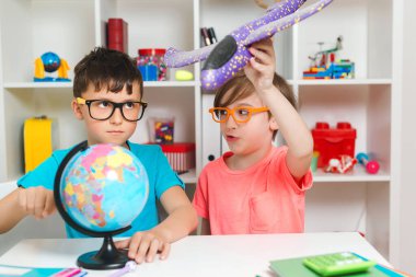 Mutlu aile yolculuk için hazırlanıyor. Sevimli çocuklar haritayı inceler ve bir seyahat rotası seçer. Mutlu çocuklar evde bir küre üzerinde çalışıyorlar. Coğrafya okuyan zeki çocuklar. Çocuklar birlikte ödev yapıyorlar..