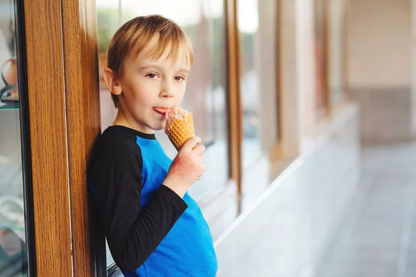 Boy eating ice cream at the city centre. Happy childhood. Cute kid on a summer walk. Tasty fruit ice-cream. Summer holidays.