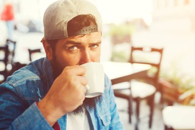 Hippi sakallı adam açık terasta kahve içer. Millet, yaşam tarzı kokarca. Şehir sokak tarzı. Kahve molası..