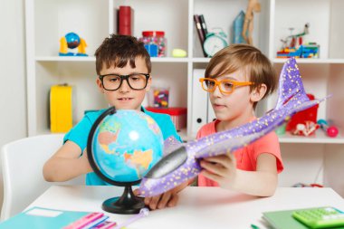 Mutlu aile yolculuk için hazırlanıyor. Sevimli çocuklar haritayı inceler ve bir seyahat rotası seçer. Mutlu çocuklar evde bir küre üzerinde çalışıyorlar. Coğrafya okuyan zeki çocuklar. Çocuklar birlikte ödev yapıyorlar..