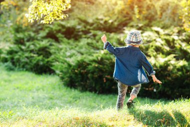 Yaz parkında koşan mutlu çocuk. Küçük şirin çocuk güneşli bir günde dışarıda eğleniyor. Mutlu ve sağlıklı bir çocukluk. Yaz havası.