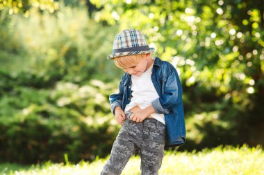 Yaz parkında poz veren mutlu bir manken. Moda, yaşam tarzı ve yaz konsepti. Güneşli bir günde mutlu çocuk yürüyüşü. Moda kıyafetleri ve yaz şapkası takan yakışıklı çocuk. Çocuk modası, yaşam tarzı..